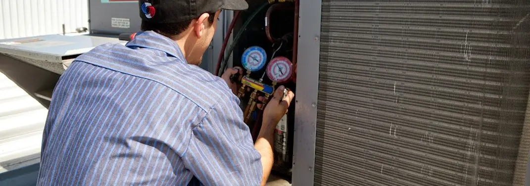 HVAC technician servicing a condenser unit in New Smyrna Beach